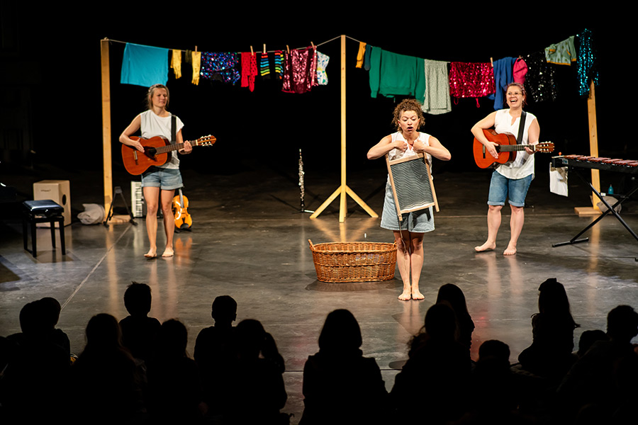 Drei Musikerinnen spielen vor einer bunt behängten Wäscheleine